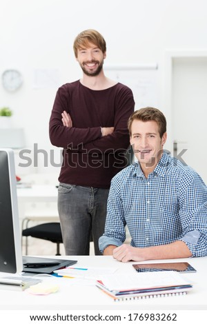 Two happy successful businessmen or business partners posing together in the office