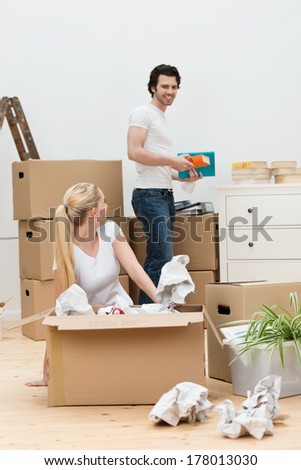 Happy young couple moving into a new home unpacking cardboard boxes on the wooden floor in the living room