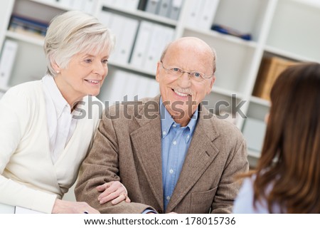 Smiling retired couple in a business meeting getting advice from their insurance broker or financial adviser as they sit in her office