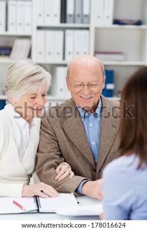 Senior couple chatting to a business broker in an office as they receive financial planning advice for their retirement