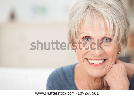 Close up facial portrait of a beautiful senior woman looking at the camera with a warm friendly smile and attentive expression