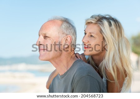 Middle-aged couple sitting in profile gazing out over the ocean on an idyllic hot sunny day at the beach