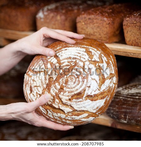 image of female bakery worker\'s hands displaying bread from shelves