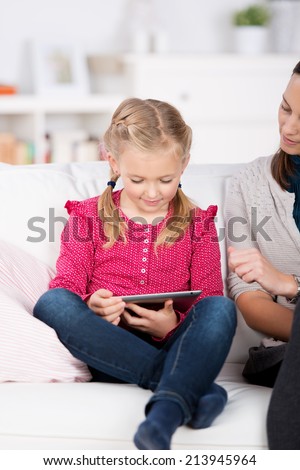Cropped woman looking at little girl use tablet pc in the house