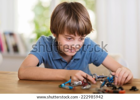 Young boy playing with a toy helicopter at home smiling a he constructs the model in an educational fun concept
