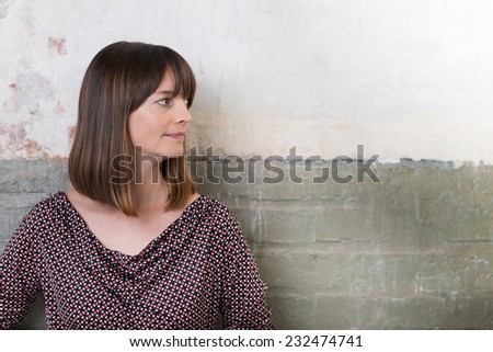 Woman in front of a two-tone grunge half painted brick wall looking into the frame with her head in profile towards copyspace