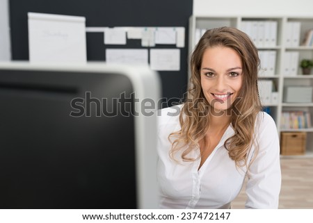 Close up Pretty Smiling Office Woman in White Long Sleeve Shirt, with Long Blond Hair, Looking at the Camera While at her Worktable.