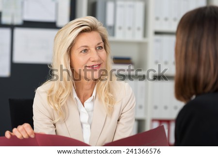 Businesswoman conducting a job interview holding the female applicants CV in her hands as she questions her in the office