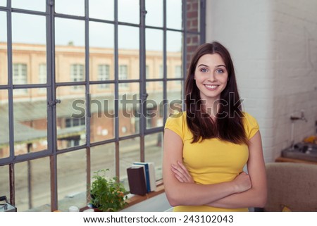Confident Pretty Young Woman in Yellow Clothing Standing Near Glass Window, with Crossed Arms, Inside the House