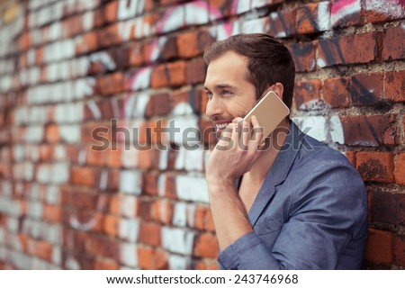 Close up Happy Handsome Young Man Calling Someone Through Mobile Phone While Leaning on Old Brick Wall