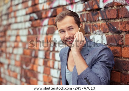 Close up Happy Young Good Looking Man Talking Someone Using Cellphone While Leaning on Old Brick Wall at the Street.