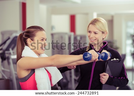 Smiling Woman Using Hand Weights While Personal Trainer Supervises Her Progress