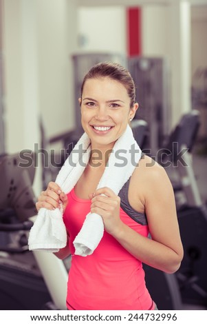 Smiling Woman Wearing Work Out Clothing with Towel Around Neck Standing in Gym