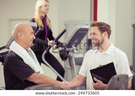 Close up Happy Old Man Shaking Hands with his Young Male Instructor at the Fitness Gym