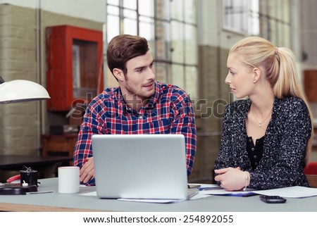 Young White Sweethearts Looking Each Other In Front of Laptop Computer at the Worktable.