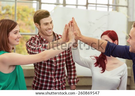 Happy smiling business team giving a high fives with their hands as they celebrate their success in the office conceptual of teamwork