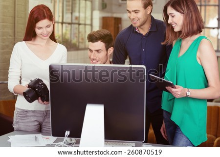 Group of Young Friends Watching Photos on a DSLR Camera Together Behind a Computer Screen.