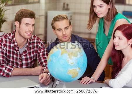 Business team looking for global markets as they plan the expansion of their business sitting around a table in the office with a globe
