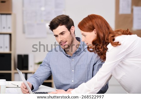 Business man and woman working on a project sharing a laptop as they discuss information on the screen