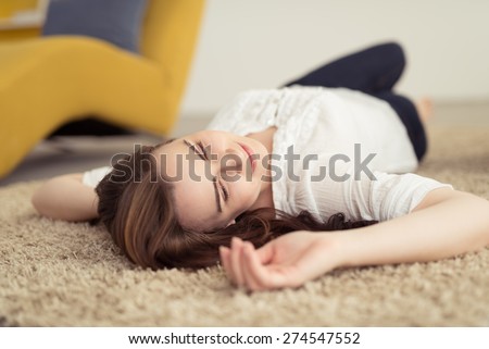 Close up Thoughtful Young Attractive Woman Lying Down on the Floor with Carpet While looking to the Right of the Frame
