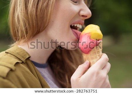 Close up Blond Teen Girl Licking Delicious Pink and Yellow Ice Cream on a Cone with Eyes Closed.
