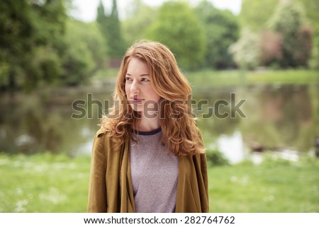 Half Body Shot of a Thoughtful Pretty Blond Girl Standing at the Lakeside While Looking Into Distance.