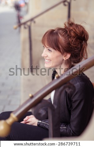 Side View of a Happy Pretty Girl, Wearing Trendy Outfit, Sitting on Stairs and Looking Into the Distance.