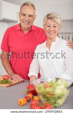 Cheerful Sweet Middle Aged Couple Standing at the Kitchen Table with Fresh Vegetables, Smiling at the Camera