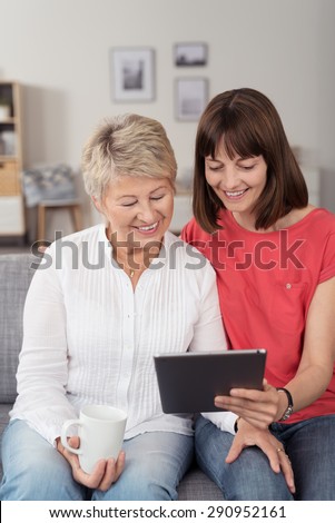 Happy Middle Aged and Young Ladies Sitting on the Couch, Looking at the Tablet Screen Together.