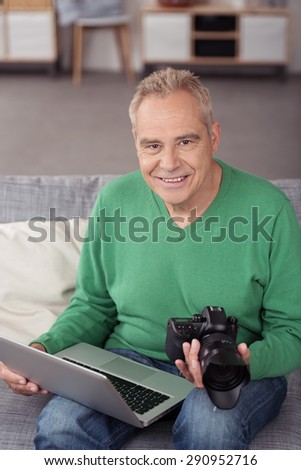 Portrait of a Smiling Senior Male Photographer with his Laptop Computer and DSLR, Smiling at the Camera