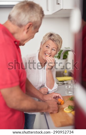 Smiling Middle Aged Wife Talking to her Husband While Preparing Food for Dinner at the Kitchen.