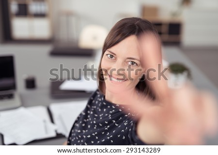 Close up Smiling Office Woman, Sitting at her Desk, Showing Peace Hand Sign Close to the Camera.