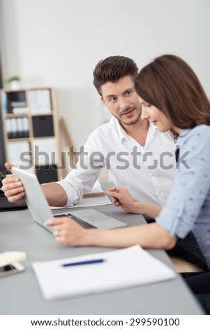 Young Businessman Admiring her Pretty Woman Busy on Laptop Computer at the Table Inside the Office.