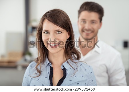 Close up Attractive Young Woman Inside the Office Smiling at the Camera In Front of her Handsome Partner.
