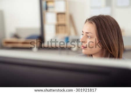 Pretty Young Office Woman Sitting at her Work Area, Looking Into Distance with Pensive Facial Expression.