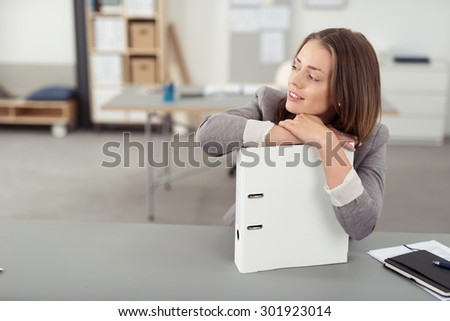 Attractive Young Office Woman Leaning on Hardboard Document Folder at her Desk While Looking Into Distance.