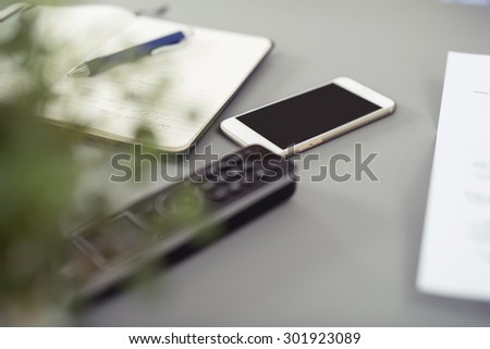 Conceptual Two Portable Phones and Notes with Pen on Top of Gray Desk of an Employee.