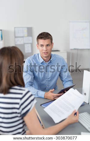 Handsome Young Office Man with Portable Table, Talking About Business to his Manager at the Table Inside the Office.