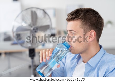 Close up Handsome Young Man Inside the Office, Drinking a Bottle Water While Looking Into Distance.