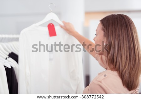 Close up Young Woman Looking at Plain White Shirt on a Hanger with Red Tag Inside the Clothing Store