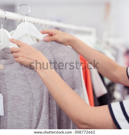 Close up Hands of a Woman Rummaging Trendy Clothes Hanging on the Rail Inside a Clothing Store