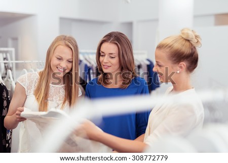 Half Body Shot of Three Pretty Girls Looking at the Quality of On-Sale Shirt Inside a Clothing Store.