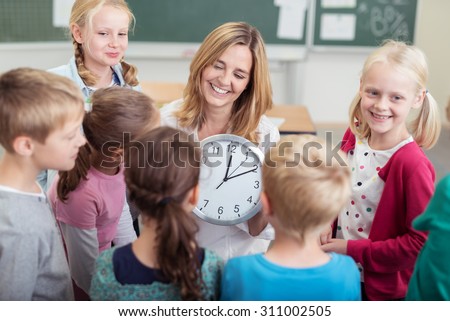 Happy Female Teacher with Wall Clock, Teaching her Students How to Read Time Inside the Classroom.