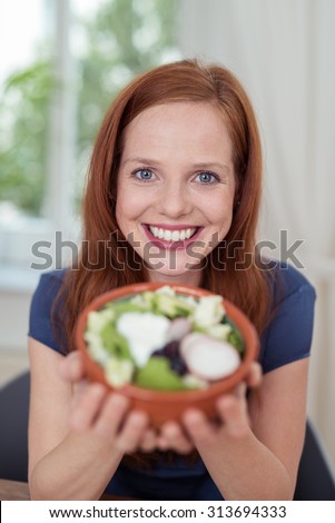 Close up Attractive Young Woman Showing a Bowl of Healthy Fresh Veggie Salad and Smiling at the Camera.