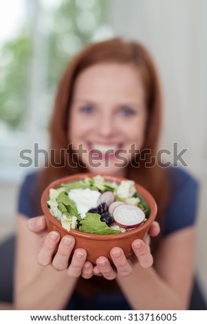 Close up Bowl of Fresh Healthy Veggie Salad held by a Smiling Woman in a Blurry Capture.