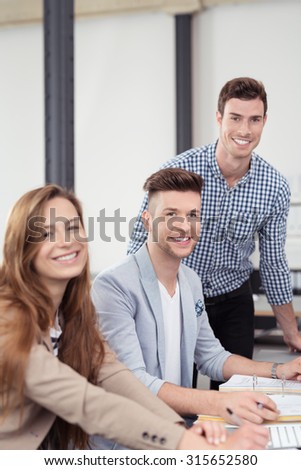 Three Young Office People Smiling at the Camera While Having a Business Meeting Inside the Boardroom.