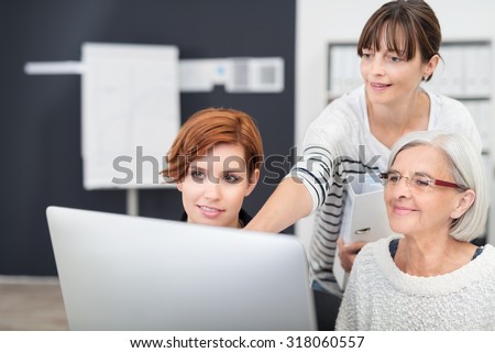 Three Office Women Looking at Computer Screen Together Inside the Workplace.