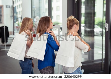 Three Happy Young Girls with Shopping Bags Over their Shoulders, Going Out From the Clothing Store.