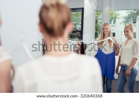 Pretty Girl Friends Checking Out Casual Shirt In Front of a Mirror Inside a Clothing Store.