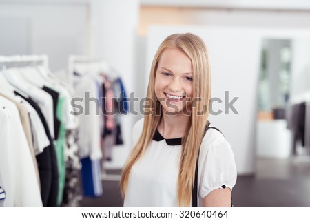 Half Body Shot of a Pretty Blond Girl Smiling at the Camera Inside the Clothing Store.